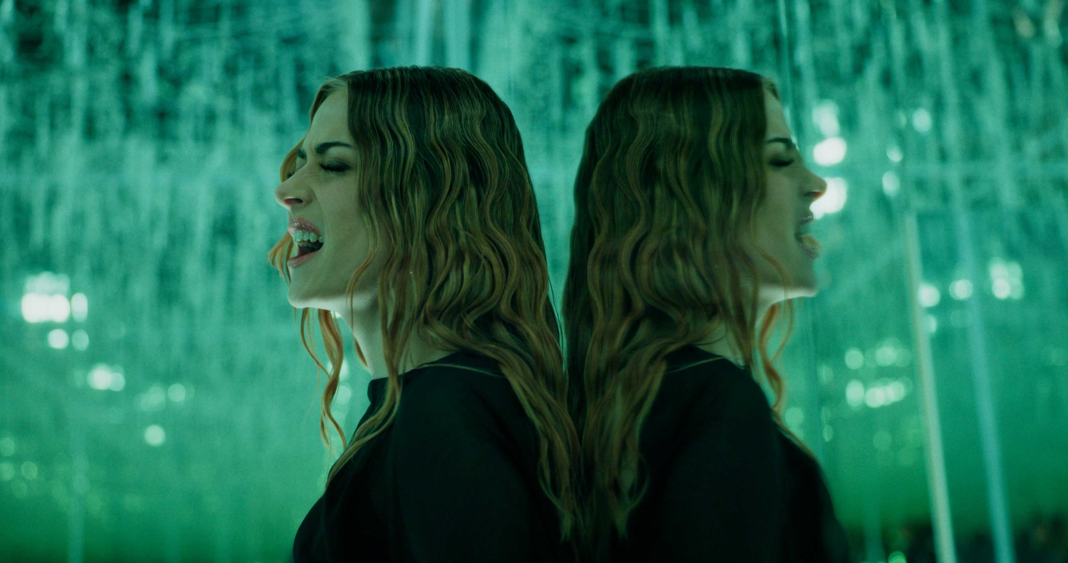 Aerial view of an alpine lakeside road with avalanche gallery; tiny sports car speeds along the shoreline.